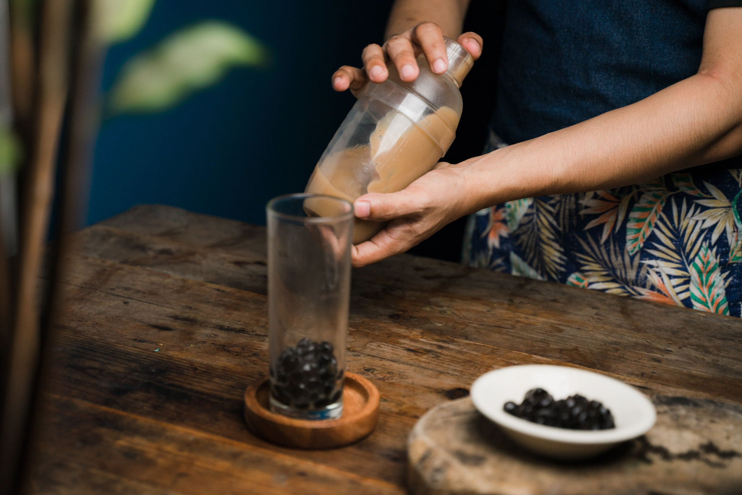 Woman Mixing Milk Tea and Glass with Tapioca on Table